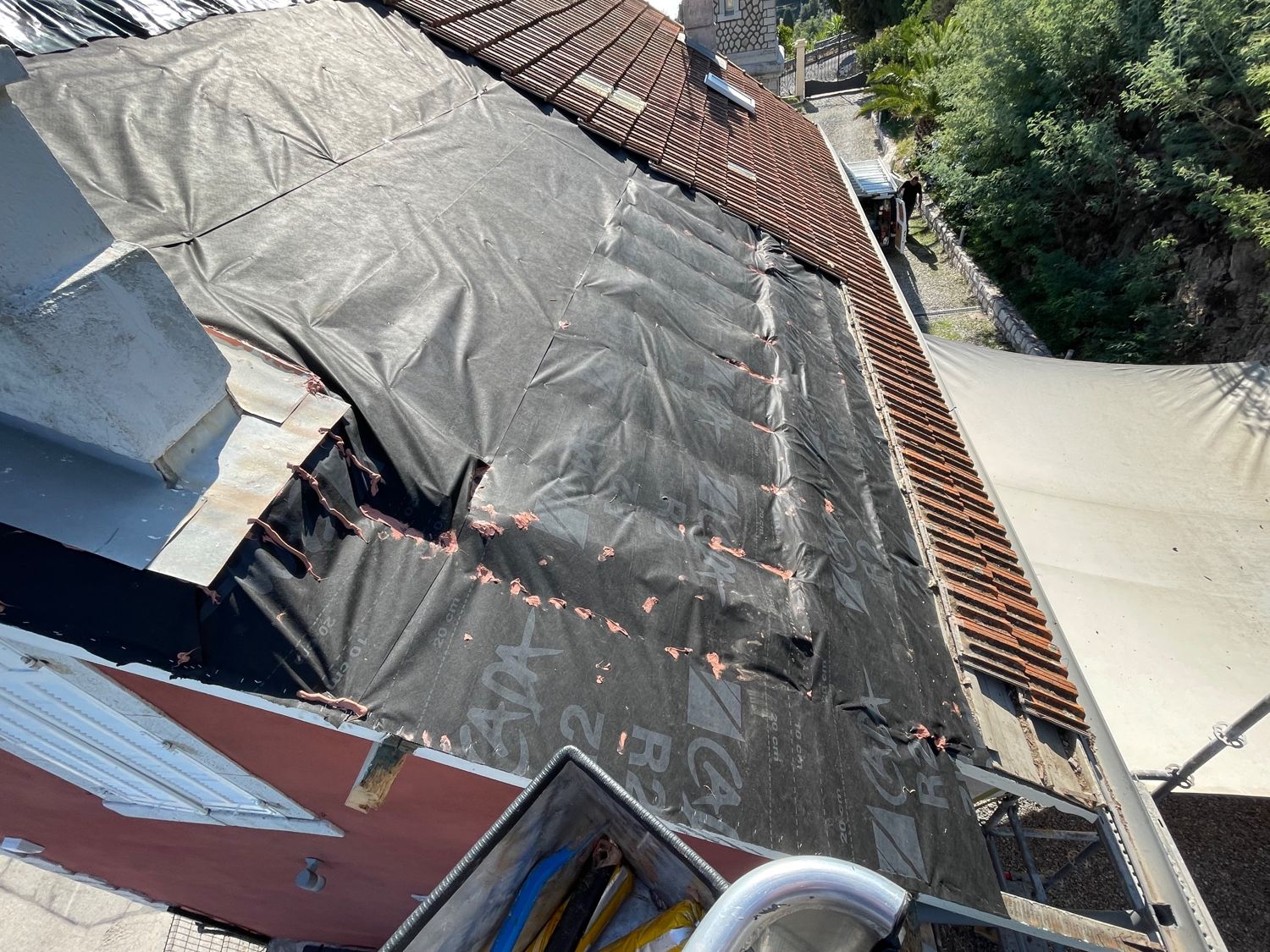 Toiture découverte protégée par un écran étanche fixé sur toute la zone, en attendant la réparation