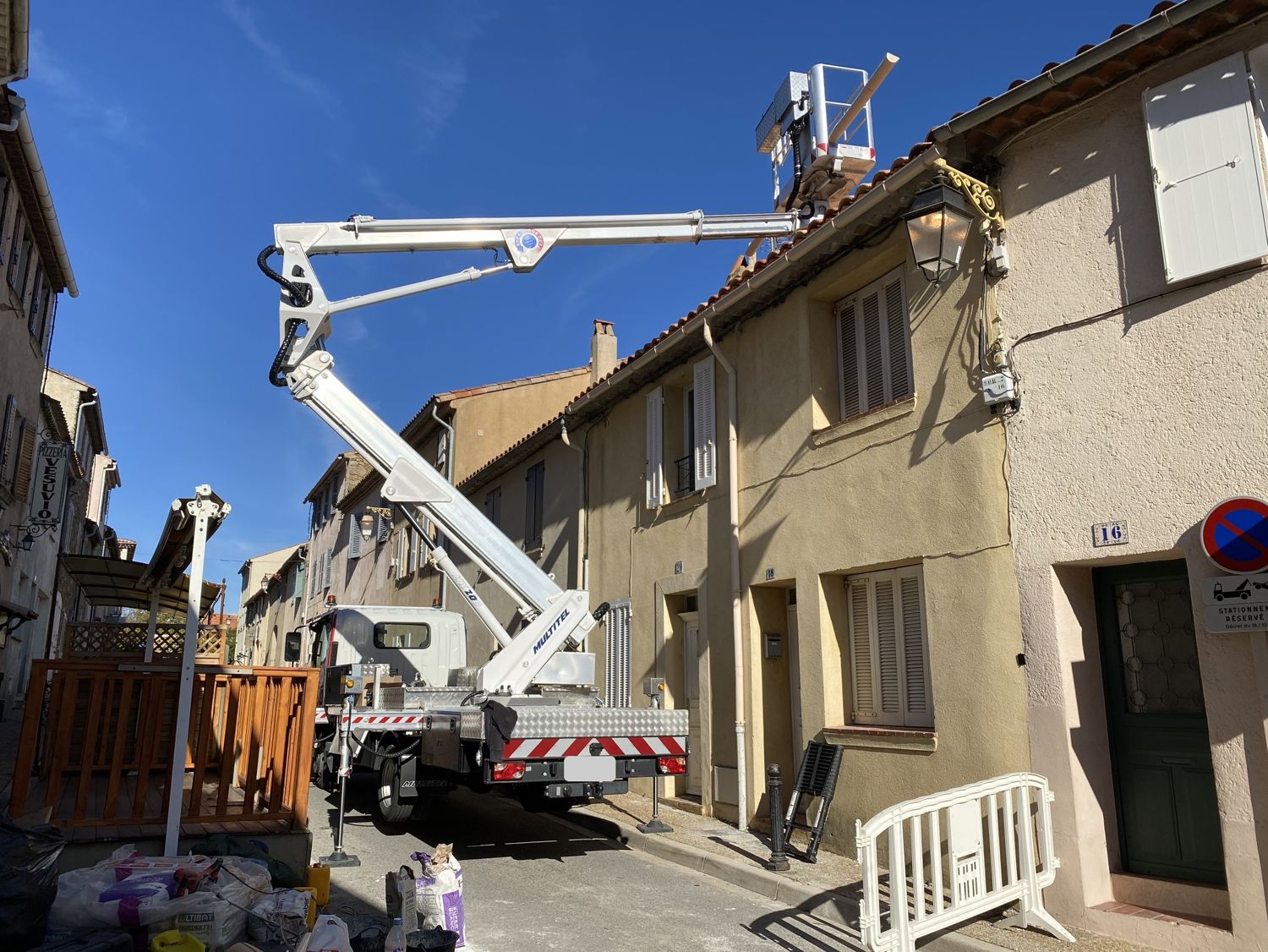 Camion-nacelle déployé au-dessus d'un toit dans une rue de village