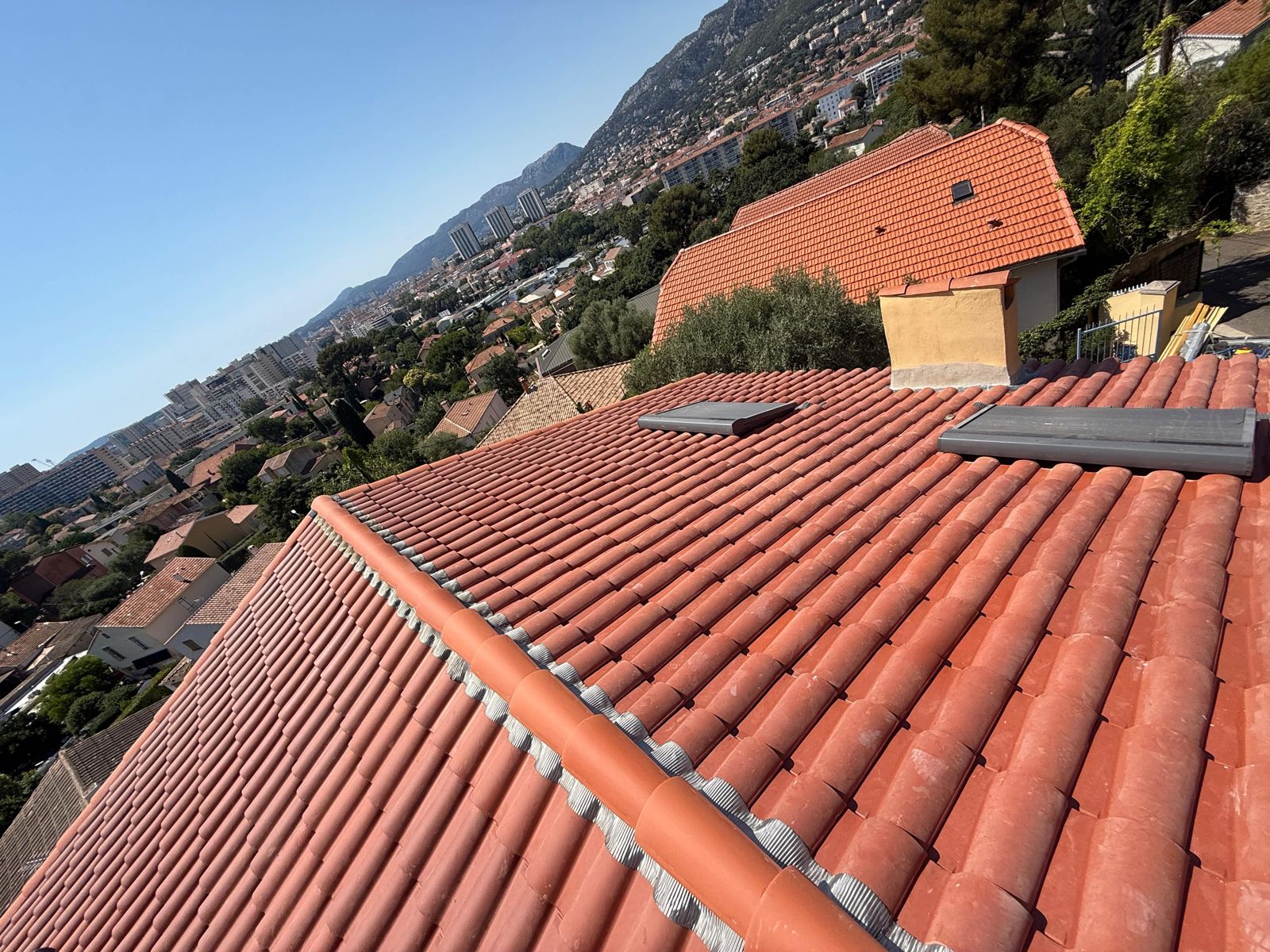Toiture rénovée en tuiles neuves avec son faîtage et deux fenêtres de toit